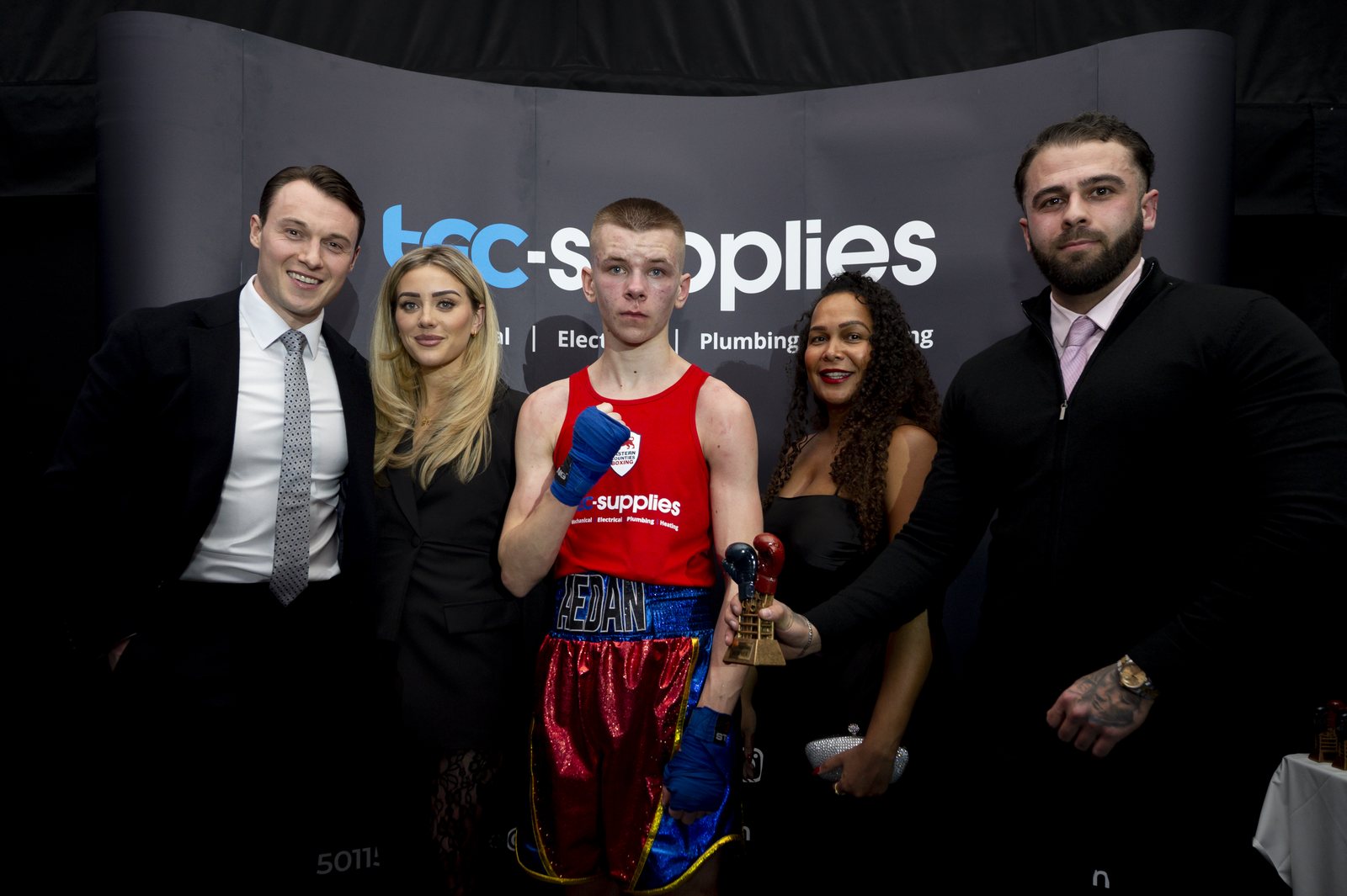 Guests in evening dress standing with a boxer in red at the charity boxing night