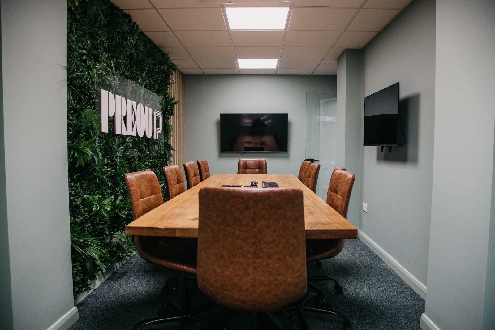 The boardroom at Radford Crescent with the Preou logo on a planted wall